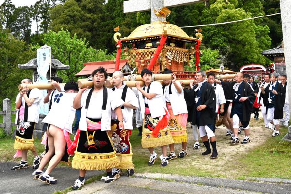 色鮮やかな化粧まわしを着けて神輿を担ぐ若者たち