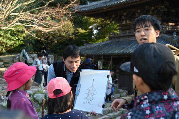 三重塔は平屋建て（1階建て）、と説明する松田技師（左）と佐々木職員