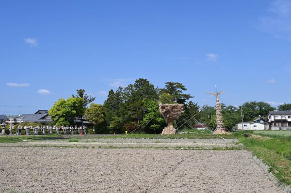 三角松明（左）と高さ9メートルほどの笠松明